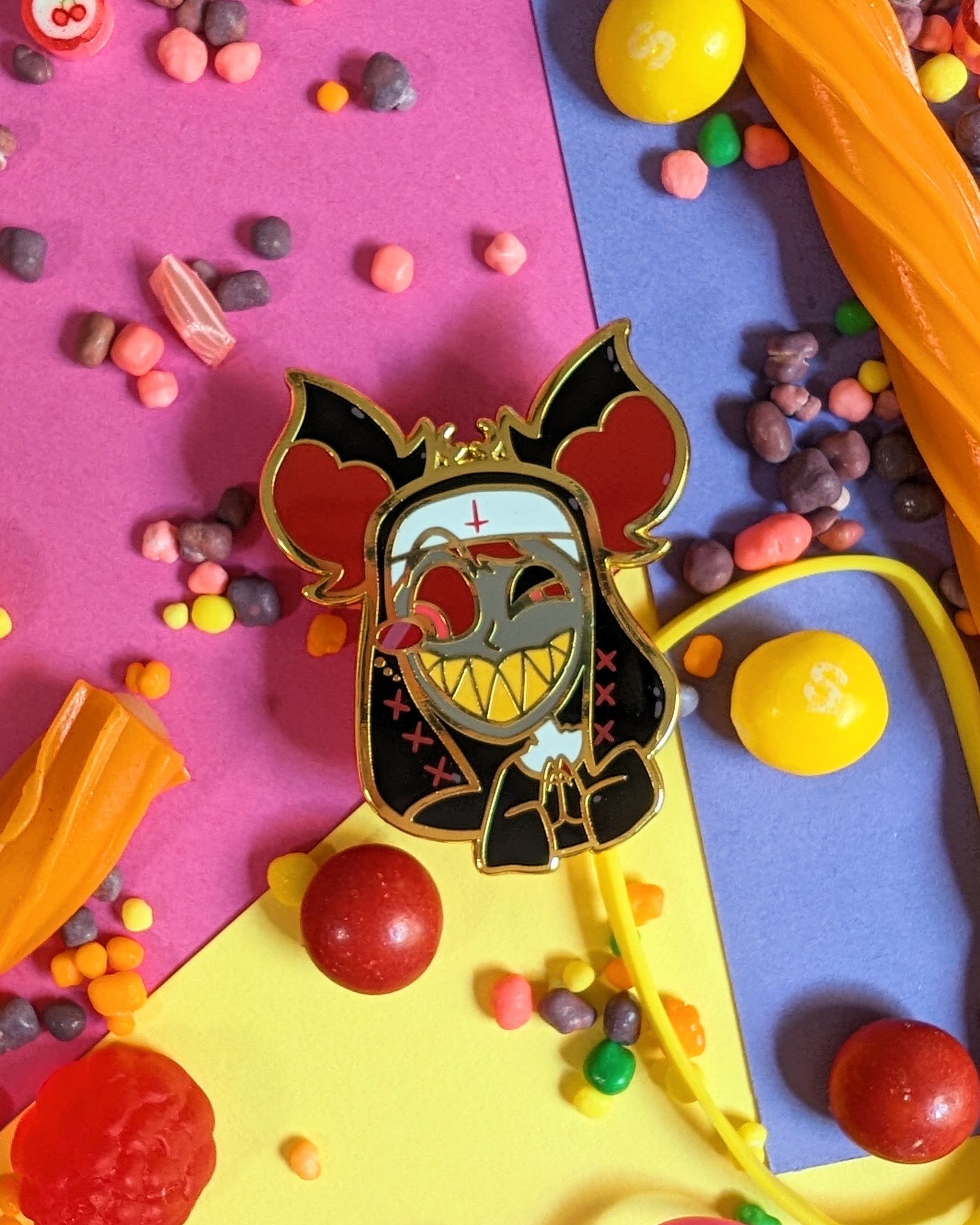 Enamel pin of Alastor from Hazbin Hotel set against a colourful background with rainbow candies