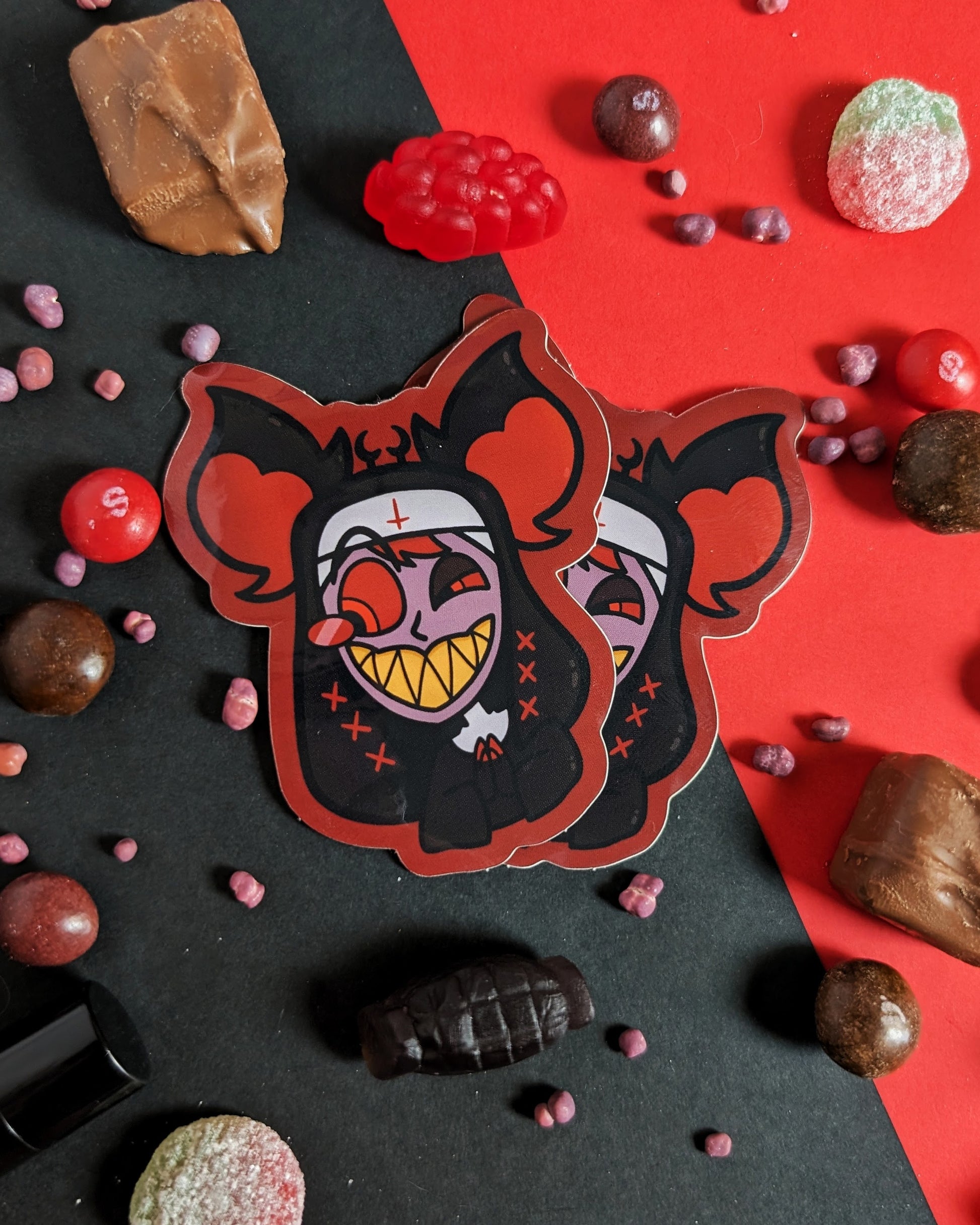 Two stickers sticker of Alastor from Hazbin Hotel dressed as a nun against red and black background with red, black, and brown candies.