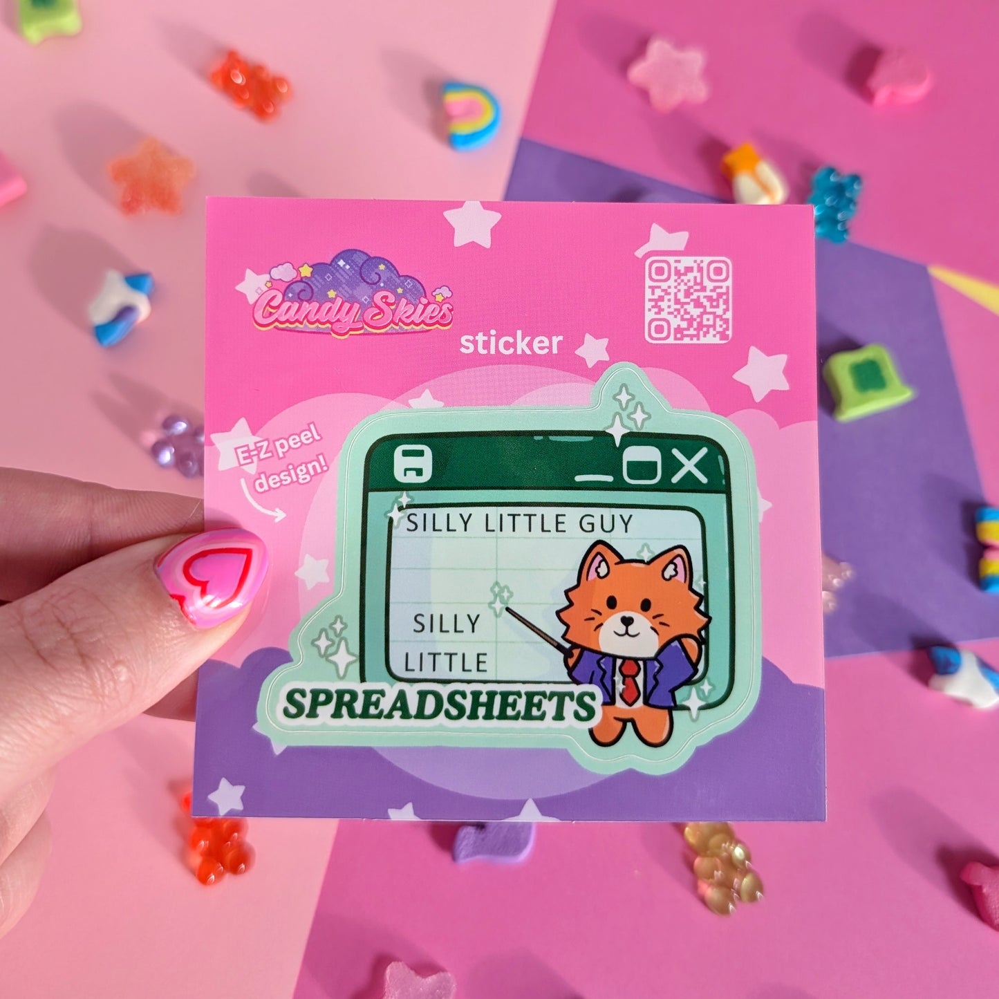 A sticker of a cat pointing at a green spreadsheet saying “silly little guy, silly little spreadsheet” against a pink and purple background