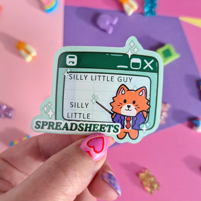 A hand holding a sticker of a cat pointing at a green spreadsheet saying “silly little guy, silly little spreadsheet” against a pink and purple background